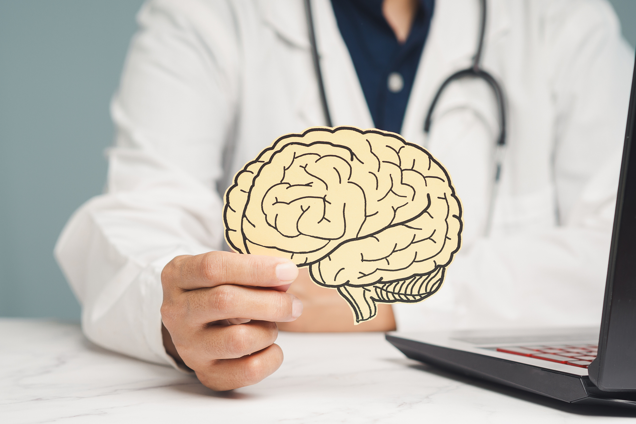 Doctor holding a brain illustration cutout, symbolizing neurology and mental health concepts.